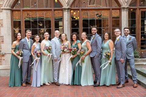 Wedding party posing in front of a brick building with large windows.