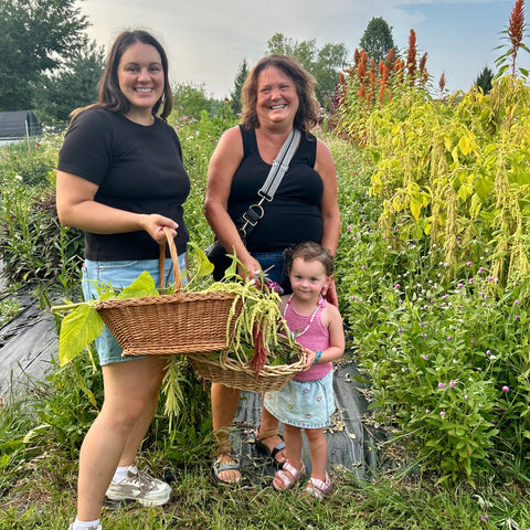 Two women and a child holding baskets of harvested flowers at First Roots Flower Farm in Oconomowoc WI 53066