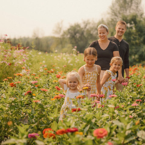Family of five, including two adults and three children, standing in a field of flowers.