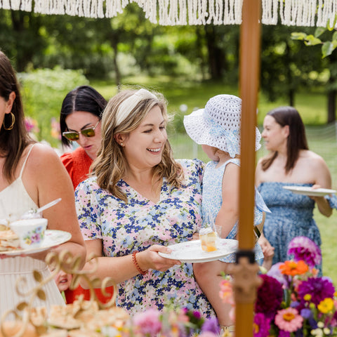 A group of women enjoying a party outdoors with floral decorations and food.