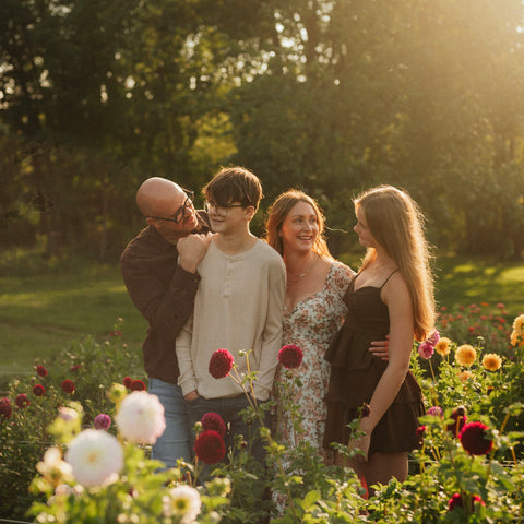 Family of four standing in a garden with flowers and greenery