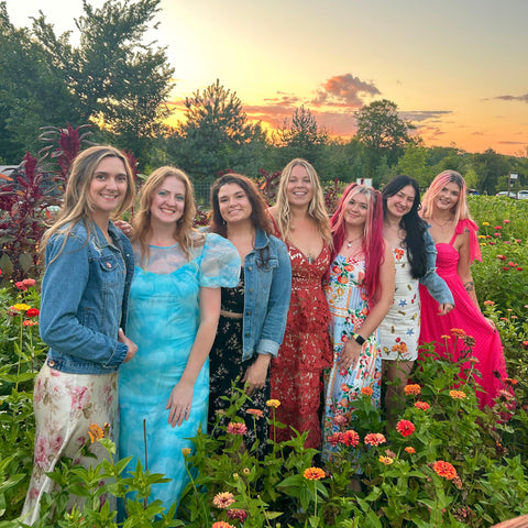 Group of women posing in a field with a sunset in the background