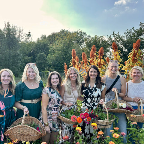 Group of women standing outdoors with baskets and flowers at First Roots Farm